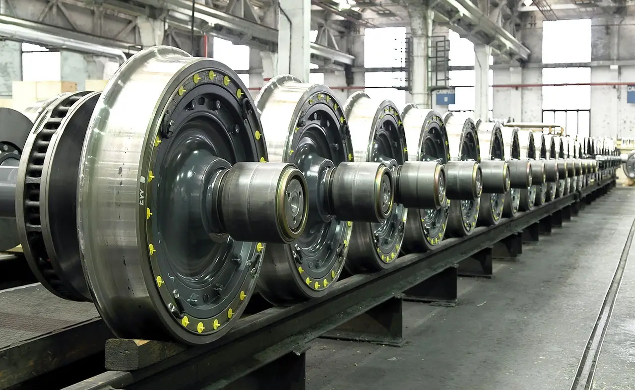 A row of finished railway wheelsets on a factory floor