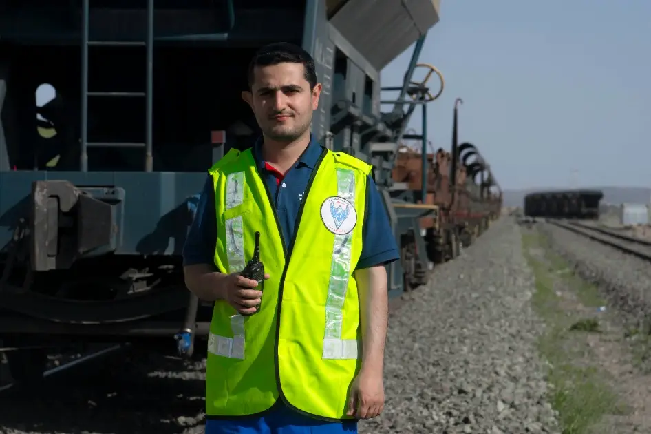 A rail technician in a high-visibility vest beside rolling stock